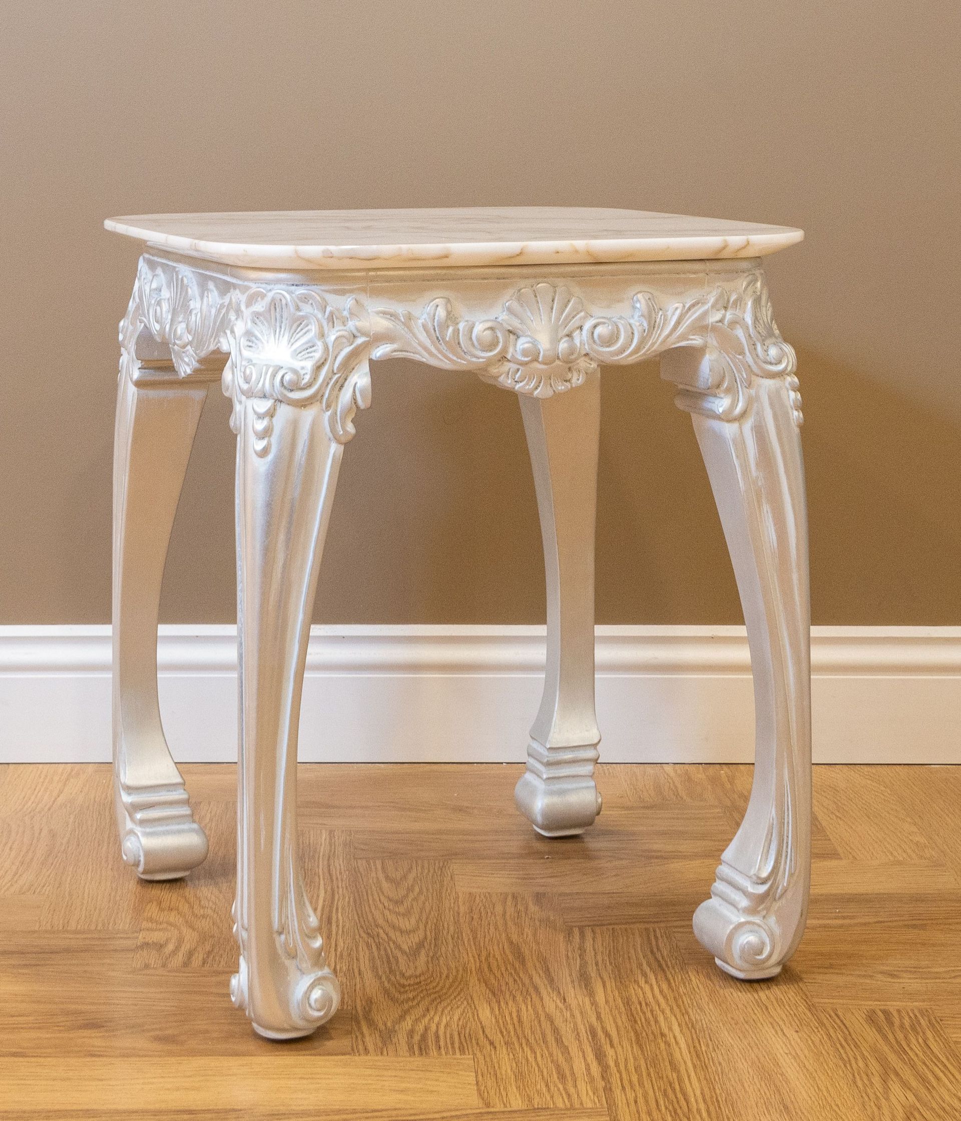 Intricately carved vintage wooden table on a polished hardwood floor with neutral background.
