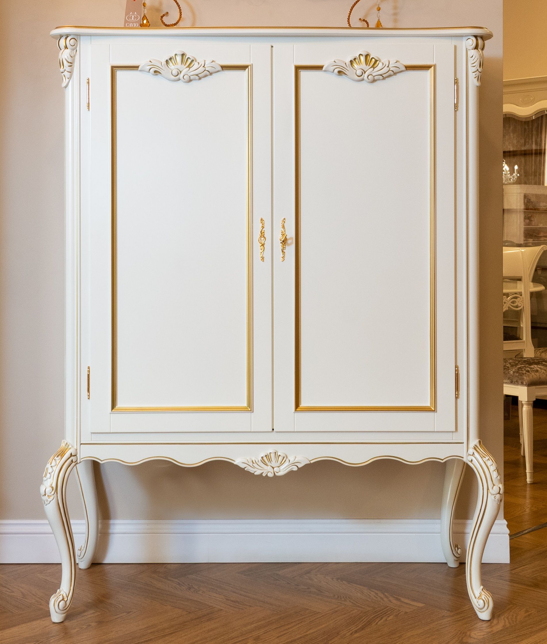 Classic vintage white armoire with ornate details in a cozy interior setting.